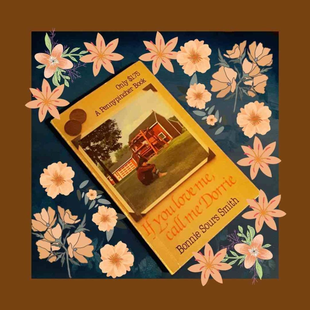 A paperback of If You Love Me, Call Me Dorrie sits on a blue background with pink flowers. ON the cover, a girl sits, hugging her knees in front of a farmhouse.