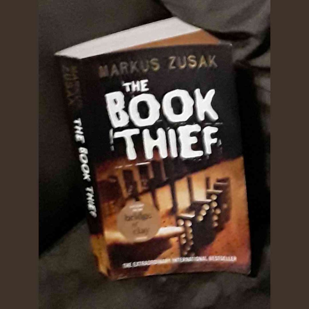 A paperback copy of The Book Thief. On the cover a set of dice sits on a table.